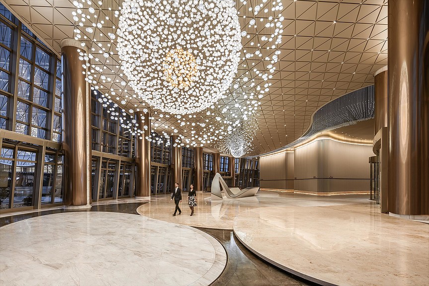 A large library with a chandelier and people walking.